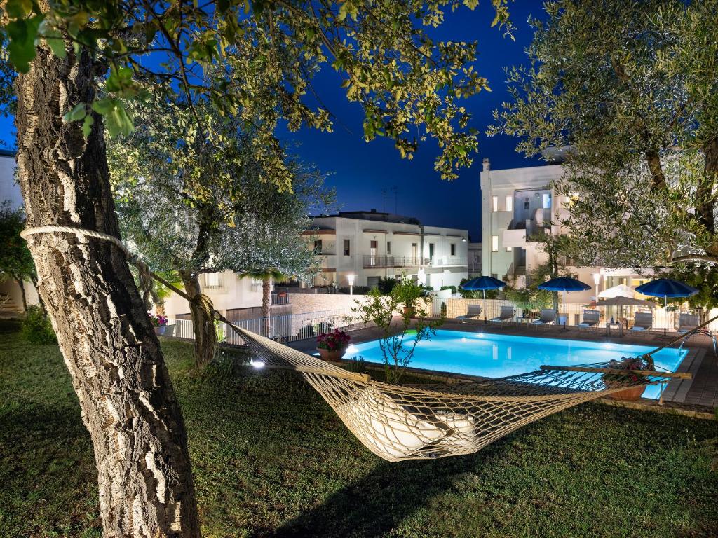 eine Hängematte, die von einem Baum neben einem Pool hängt in der Unterkunft Hotel Colle Del Sole in Alberobello