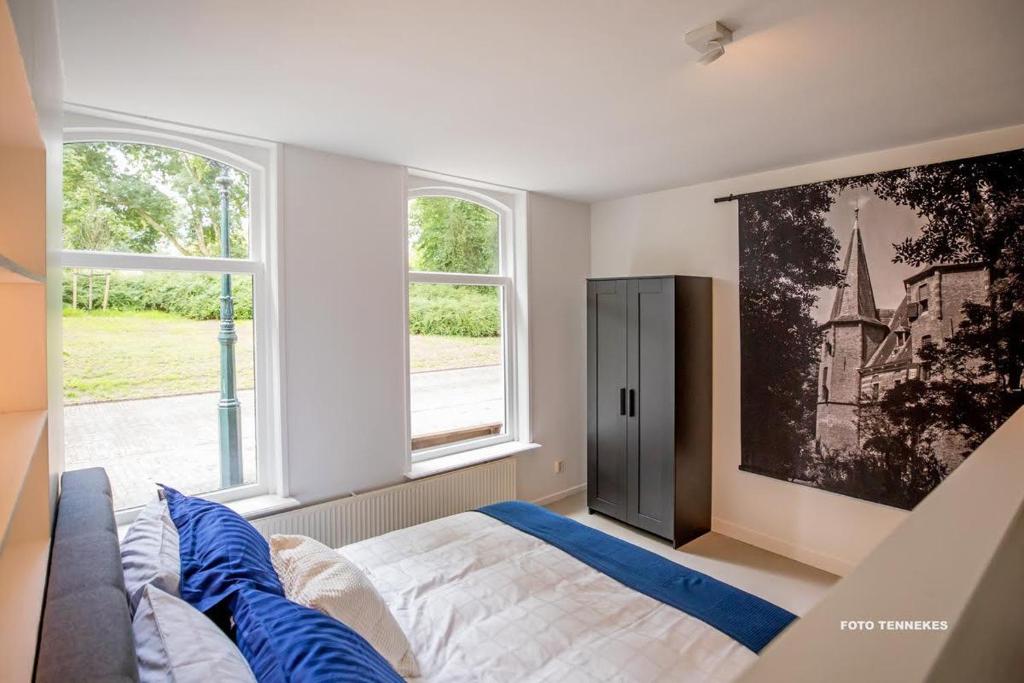 a bedroom with a bed and two windows at Bed&Breakfast Tussen de Poorten in Kampen