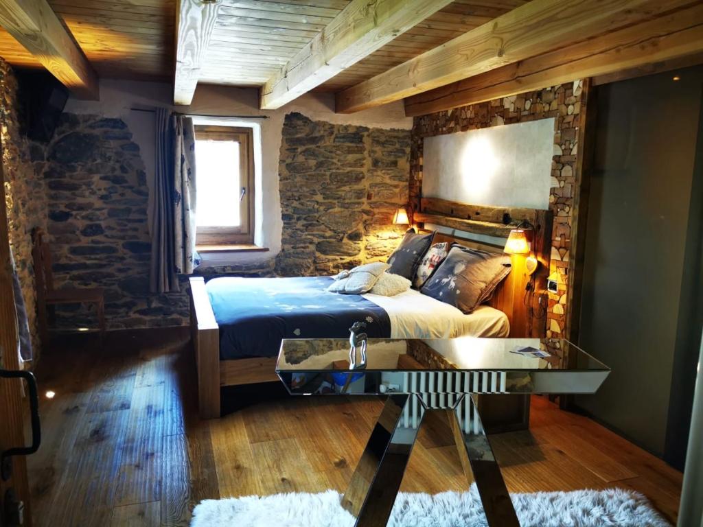 a bedroom with a bed and a stone wall at Maison Le Cler in Valtournenche