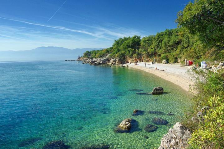 plaża z ludźmi siedzącymi na piasku i wodzie w obiekcie Lori Apartment w mieście Kostrena