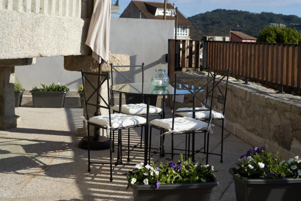 einen Tisch und Stühle auf einer Terrasse mit Blumen in der Unterkunft Views and Beds in Pontevedra