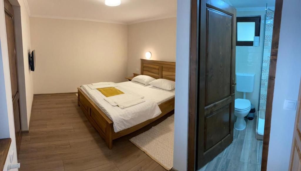 a small bedroom with a bed and a bathroom at Hanul Ursilor in Chişcău