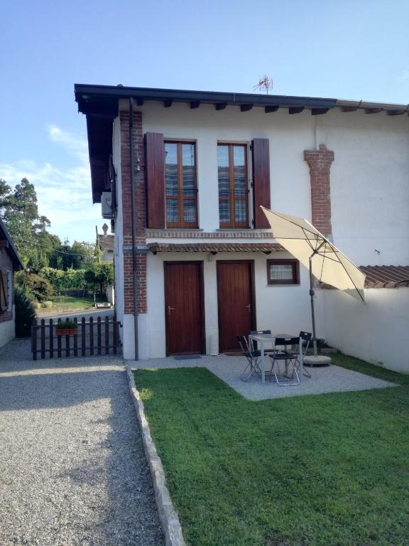 a house with a table and an umbrella in the yard at Country Corner Lago Maggiore in Divignano