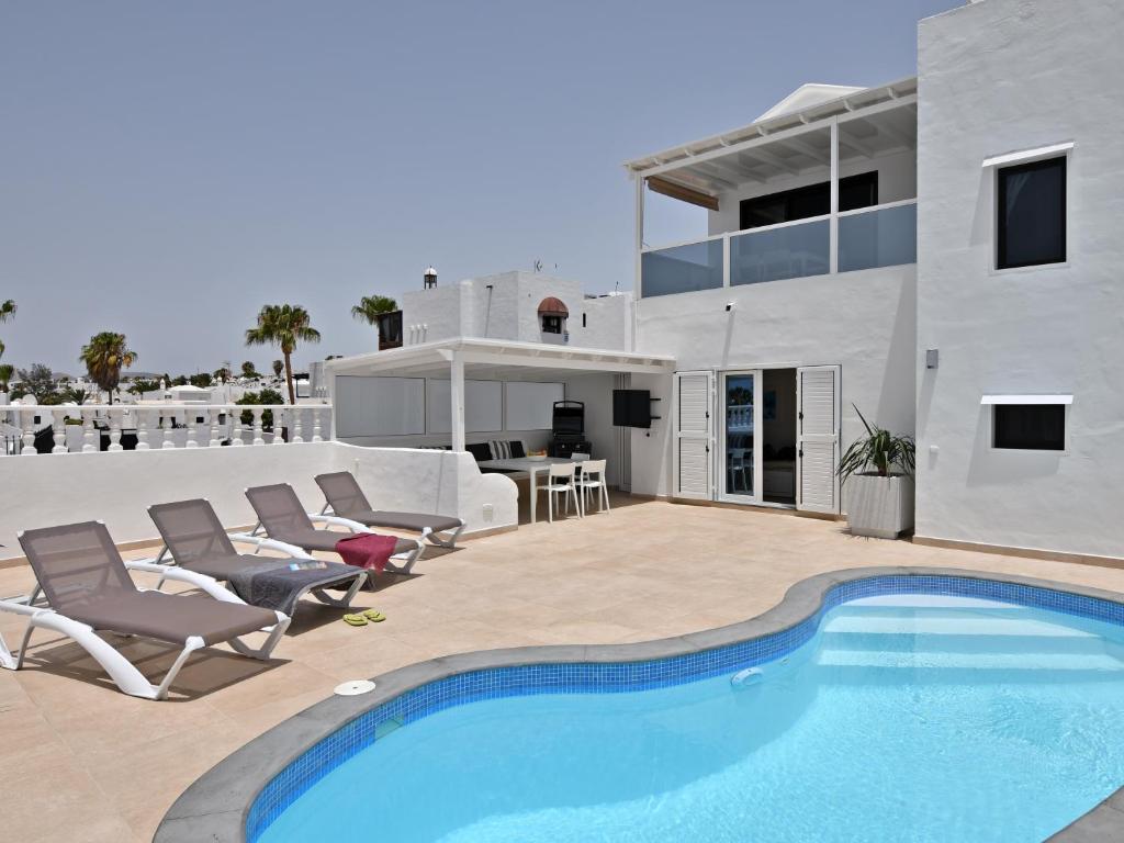 a villa with a swimming pool and patio furniture at Villa Zonzamas in Puerto del Carmen