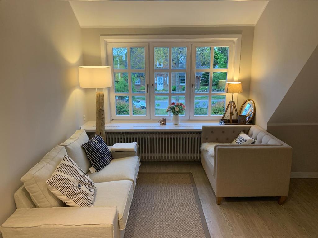 a living room with two couches and a window at Keitum - hochwertig und gemütlich Wohnen unter Reet in Keitum