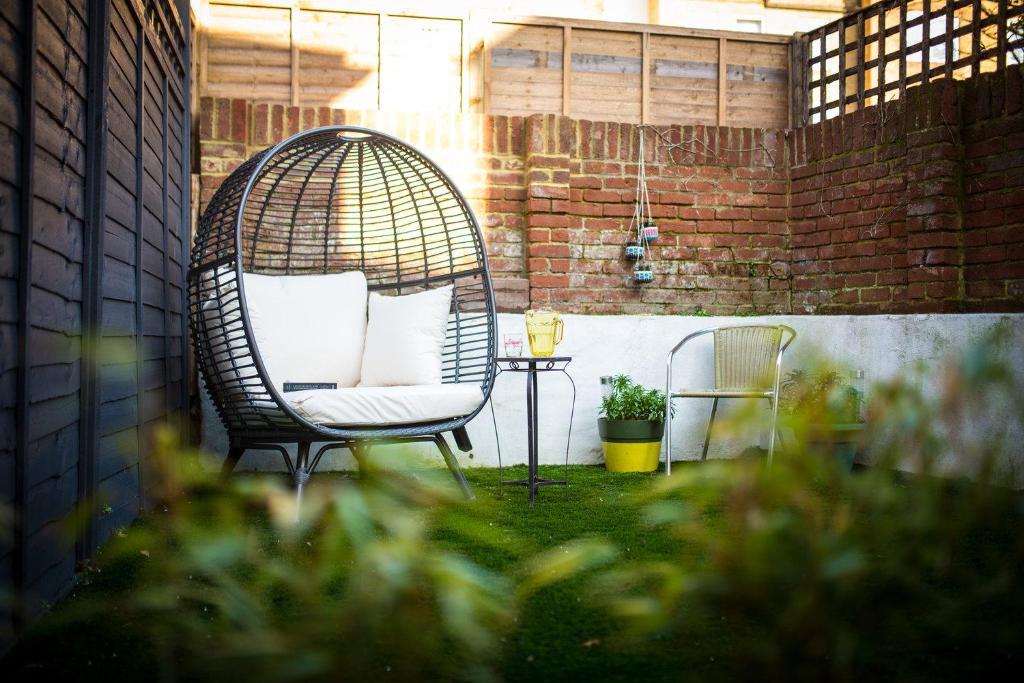 a rattan chair sitting in a yard with a table at Old Barrel Store - Old Town. Parking & Garden in Margate