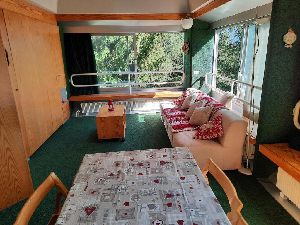 ein Wohnzimmer mit einem Tisch, einem Sofa und einem Fenster in der Unterkunft Vetrate sul bosco in Marilleva