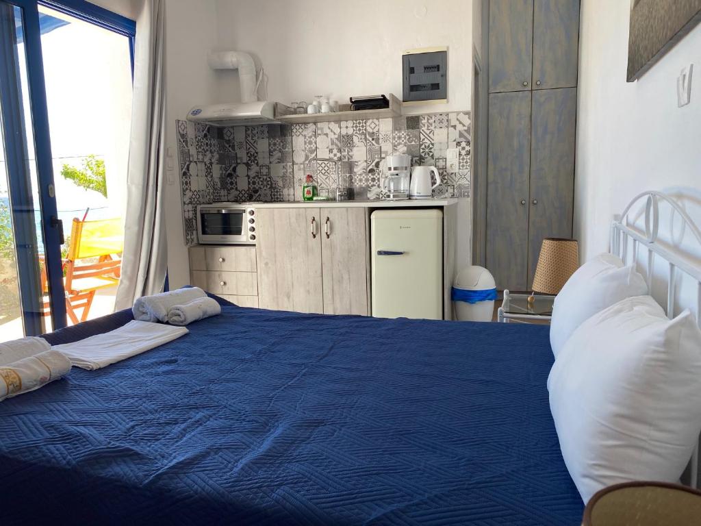 a bedroom with a blue bed and a kitchen at Kionia Apartments in Kerames