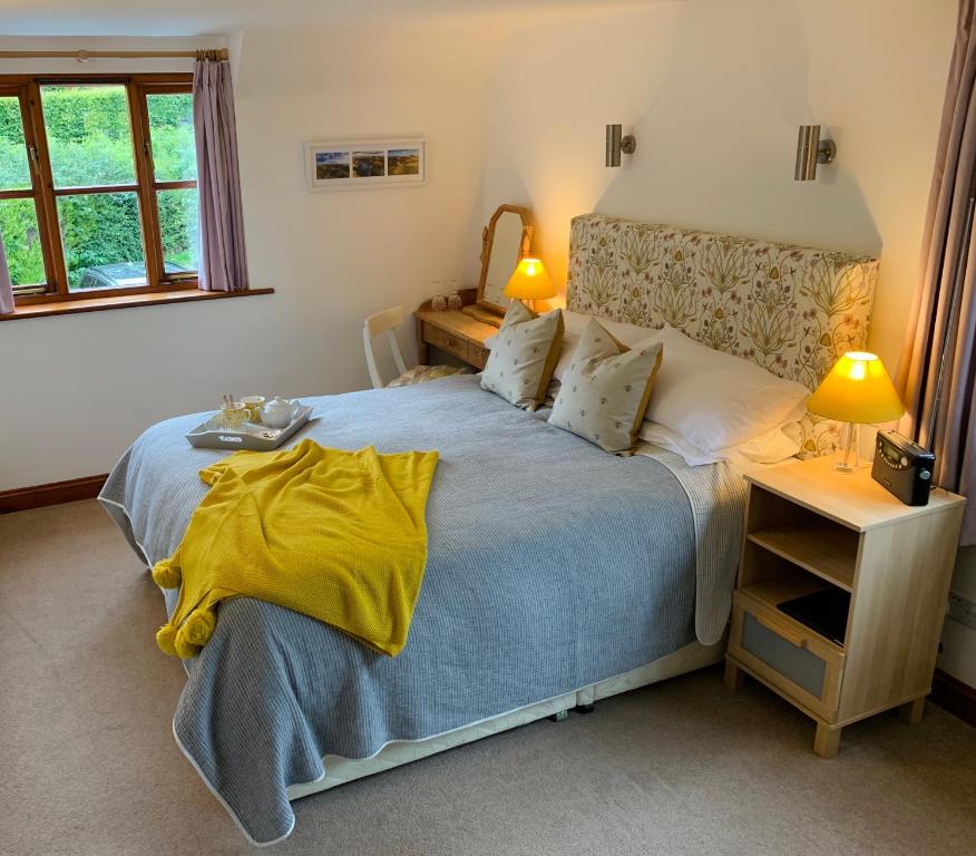 a bedroom with a large bed with a yellow blanket at Sayang House in Church Stretton