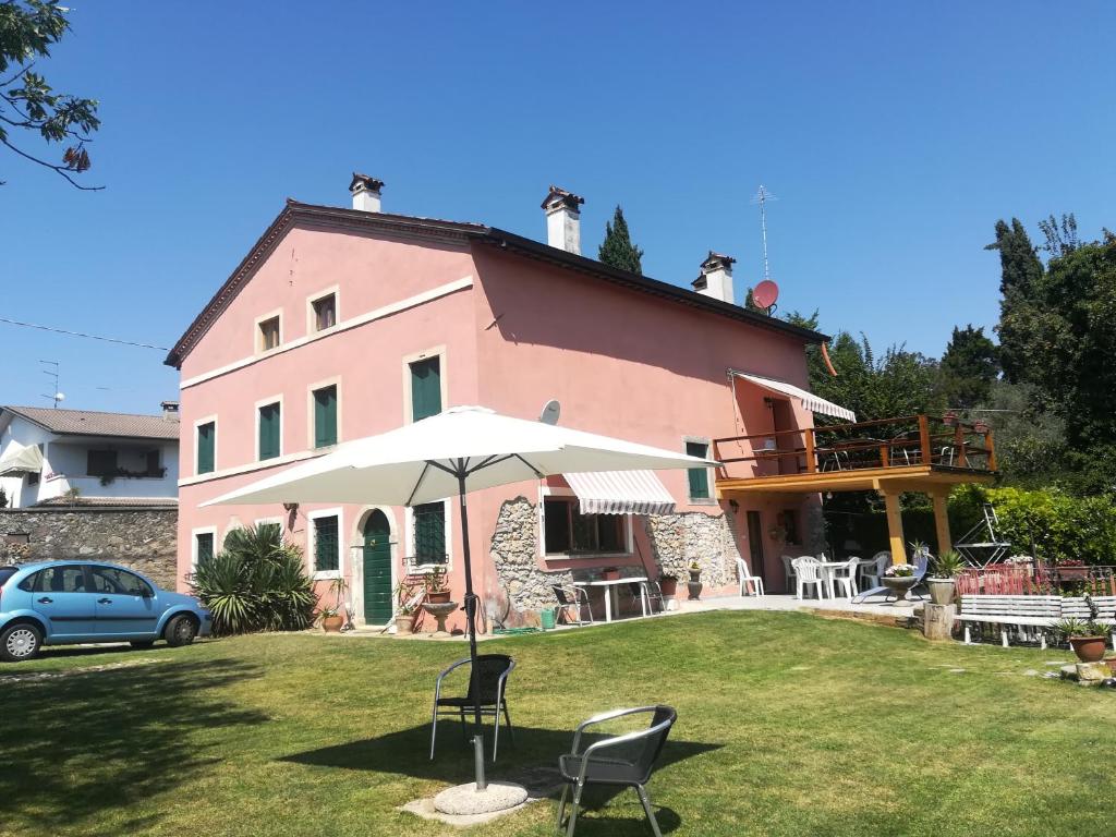 una casa rosa con sombrilla y sillas en el patio en Alloggio Alla Collina, en Arcugnano