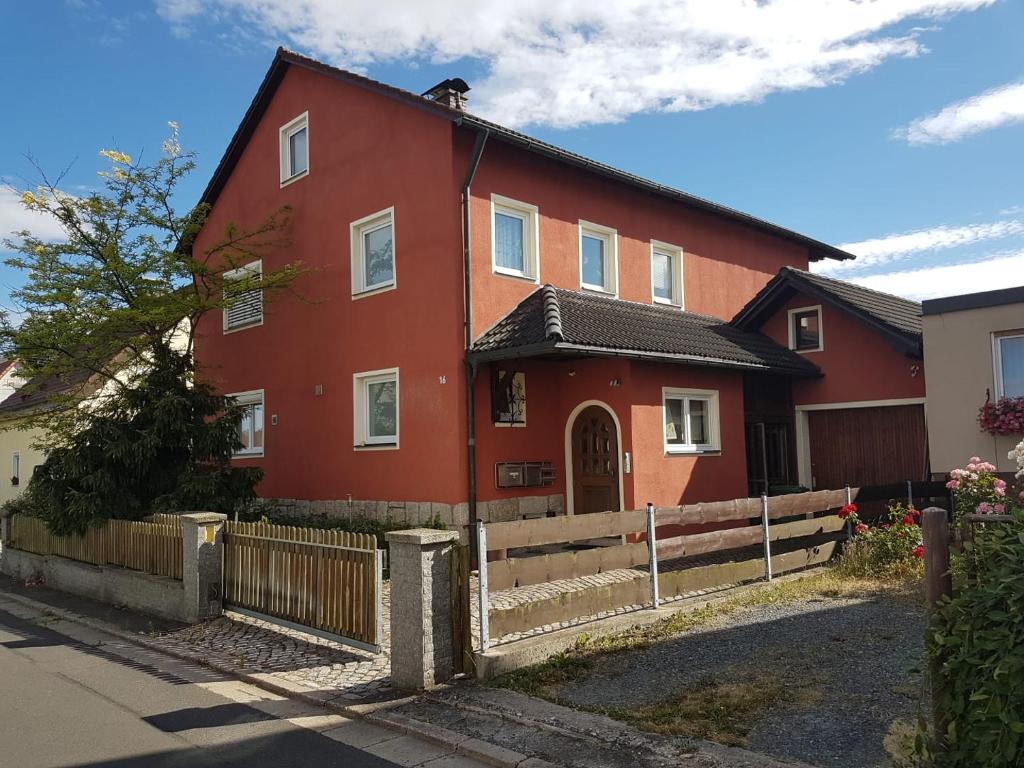 a red house with a fence in front of it at Gästehaus Aurelia in Wiesau