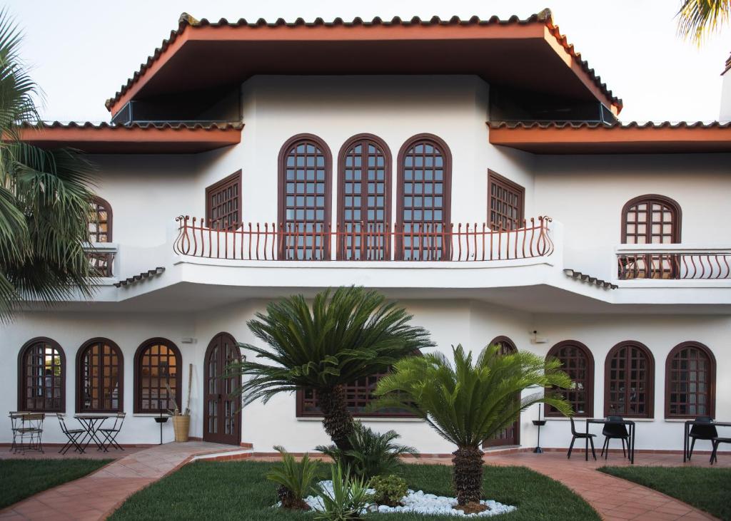 a house with a balcony and palm trees at Mami Sabaudia Hotel in Sabaudia