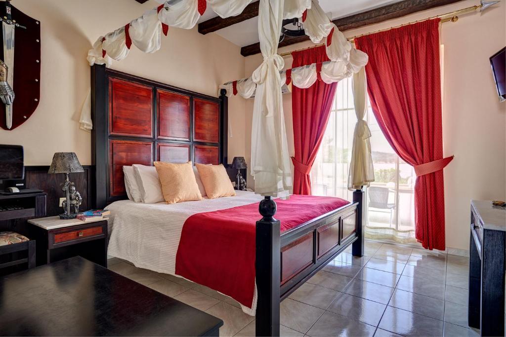 - une chambre avec un grand lit et des rideaux rouges dans l'établissement Castello Di Cavallieri Suites & Spa - Adults Only, à Faliraki