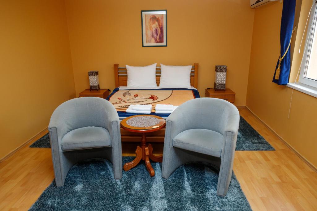 a bedroom with a bed with a table and two chairs at Guest house Mali homtel in Subotica