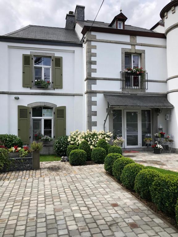 奧通的住宿－La conciergerie，白色的房子,设有绿色百叶窗和庭院