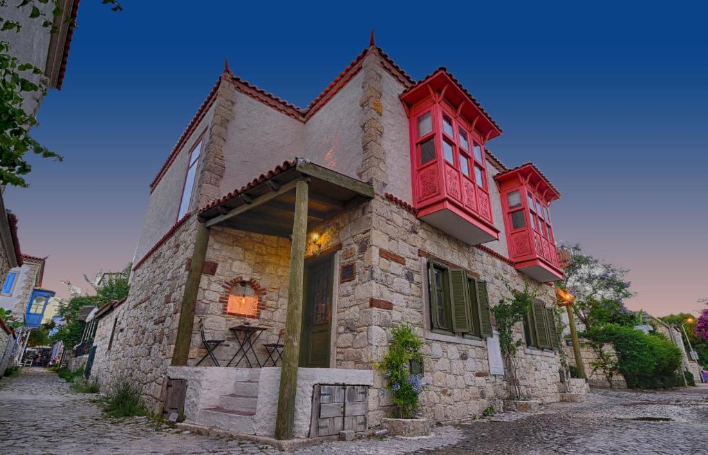 an old stone house with red windows on a street at Perla Rossa Alacati in Alacati