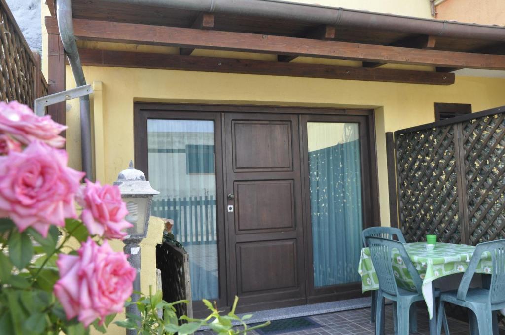 un patio con una puerta de madera y una mesa con rosas rosas en Jajo Apartments, en Castelsardo
