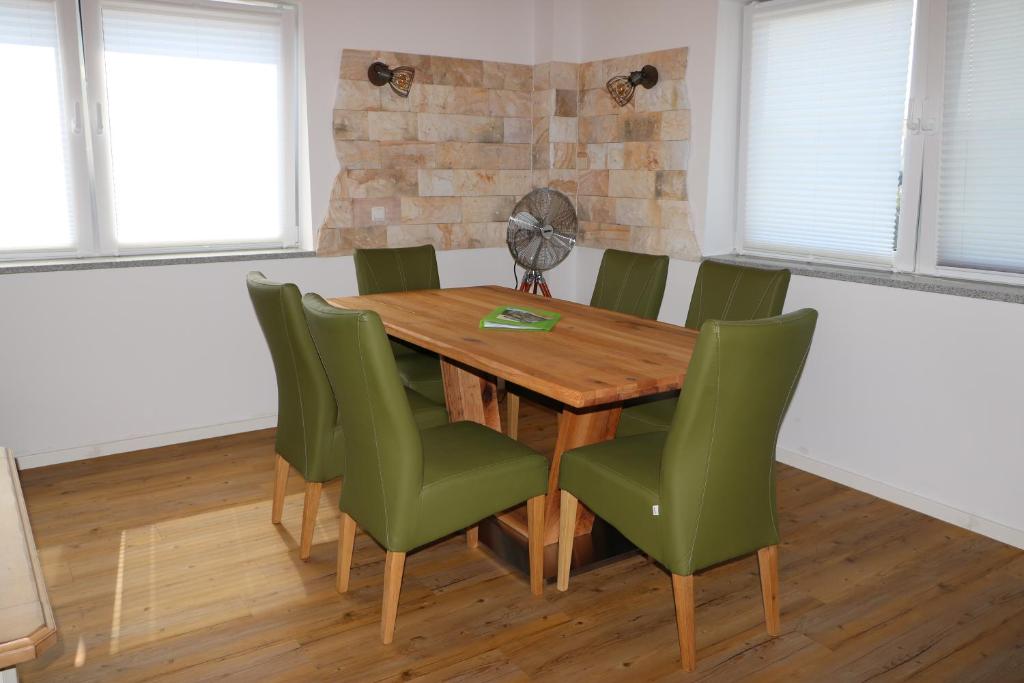 a dining room with a wooden table and green chairs at Ferienwohnung Bittner in Wernberg-Köblitz