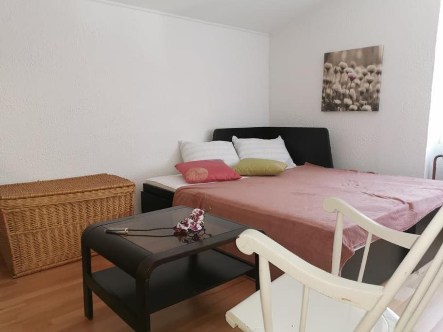 ein Schlafzimmer mit einem Bett, einem Stuhl und einem Tisch in der Unterkunft APARTMA LINDAU in Lendava