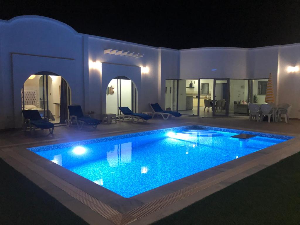 una gran piscina en una casa por la noche en VILLA NOUR DJERBA plain pied haut de gamme piscine proche de la plage en Midoun