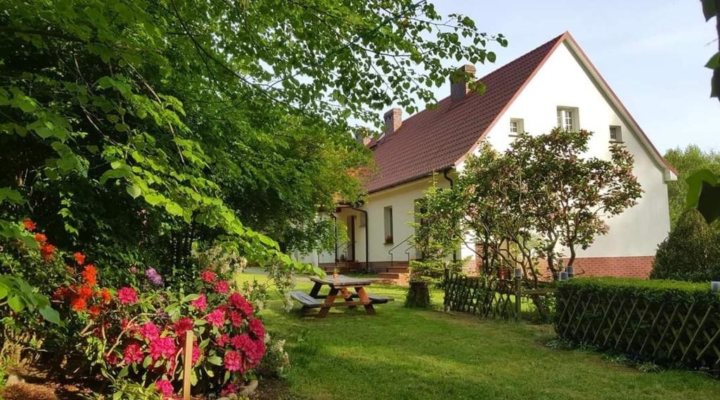 a house with a picnic table and flowers in the yard at Agroturystyka Rębowo in Kłodawa