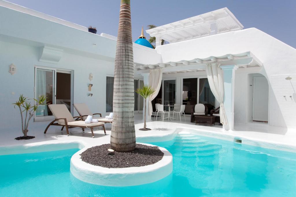 a villa with a palm tree in the middle of a swimming pool at Villa 44 in Corralejo