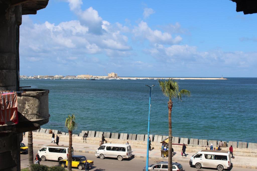 een groep auto's geparkeerd op een strand met de oceaan bij Ithaka Hostel in Alexandrië