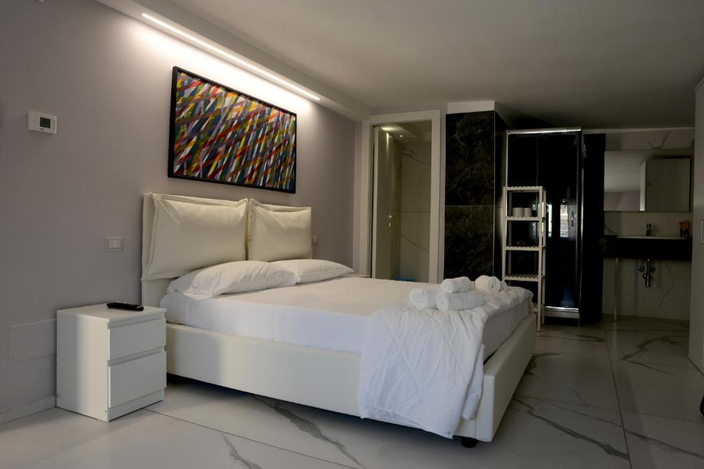sypialnia z białym łóżkiem i obrazem na ścianie w obiekcie Dimore Pietrapenta Apartments, Suites & Rooms - Via Lucana 223, Via Piave 23, Via Chiancalata 16 w mieście Matera