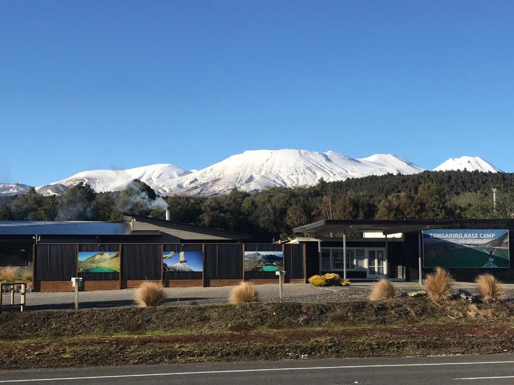 a building with snow covered mountains in the background at Tongariro Holiday Park in Tongariro