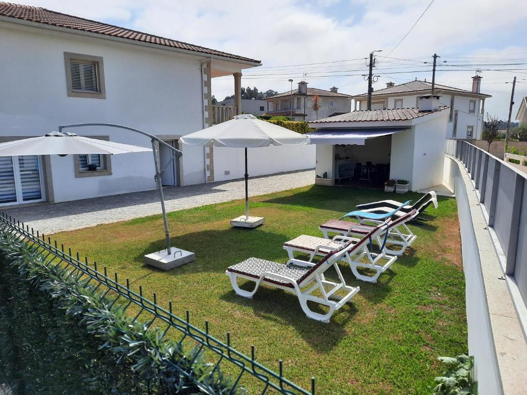 a patio with lounge chairs and umbrellas on a yard at Alojamento Rio Neiva in Boticas