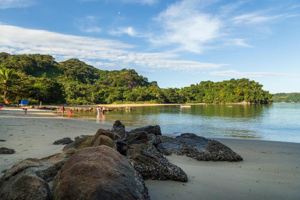 a beach with rocks on the sand and water at Residencial Atlântico Sul in Paraty