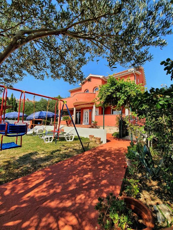 a playground in front of a pink house at Petra Apartment in Rab