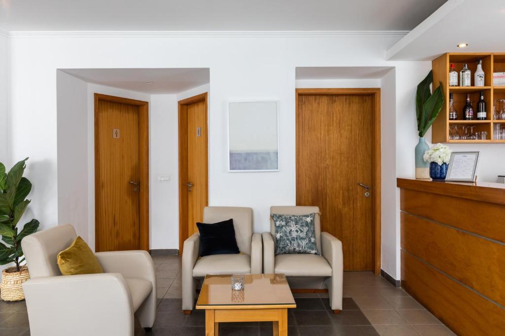 a living room with two chairs and a table at Hotel Arcanjo in Rosário-Lagoa