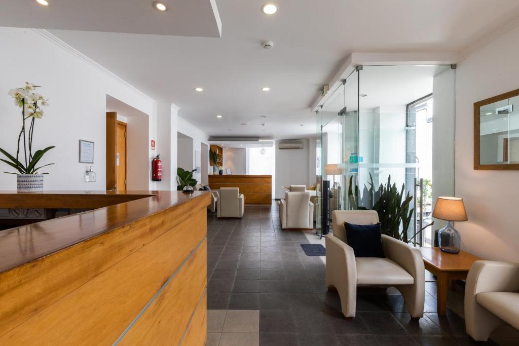 an office lobby with a reception desk and chairs at Hotel Arcanjo in Rosário-Lagoa