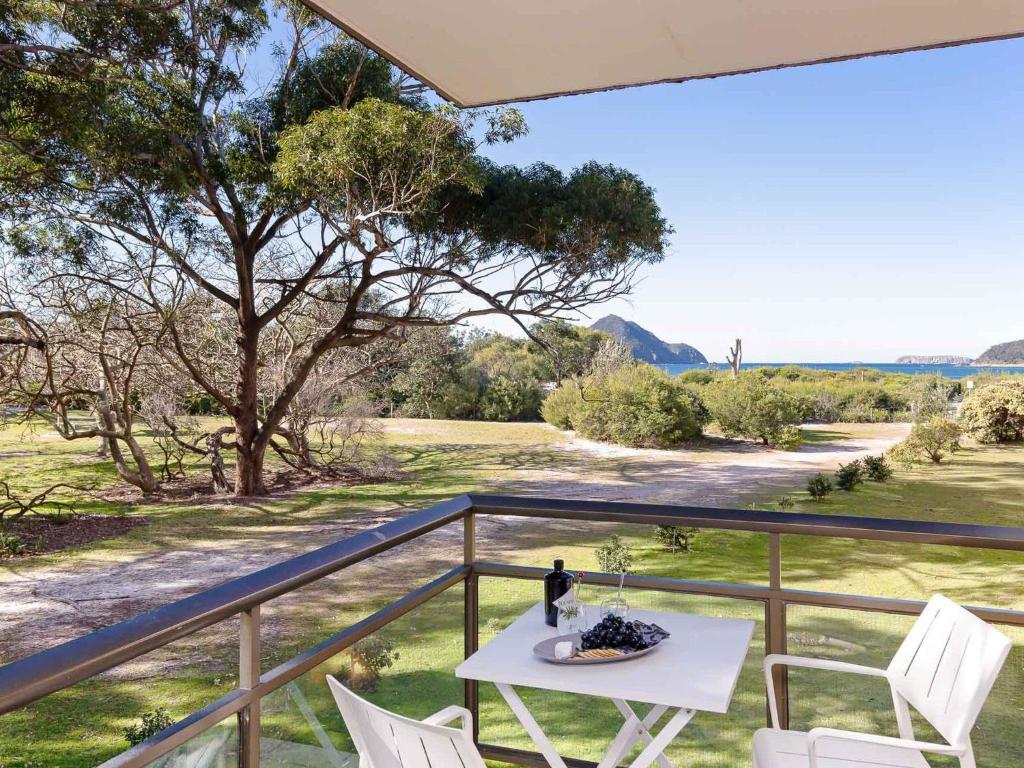 uma mesa e cadeiras em uma varanda com vista em Intrepid 1 3 Intrepid Close Amazing views of Shoal Bay only 100m from the Beach em Shoal Bay