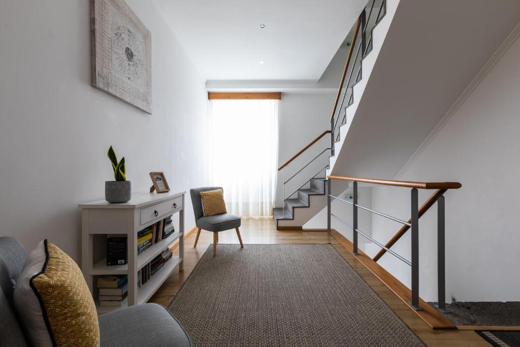 a living room with a staircase and a chair at Hotel Arcanjo in Rosário-Lagoa