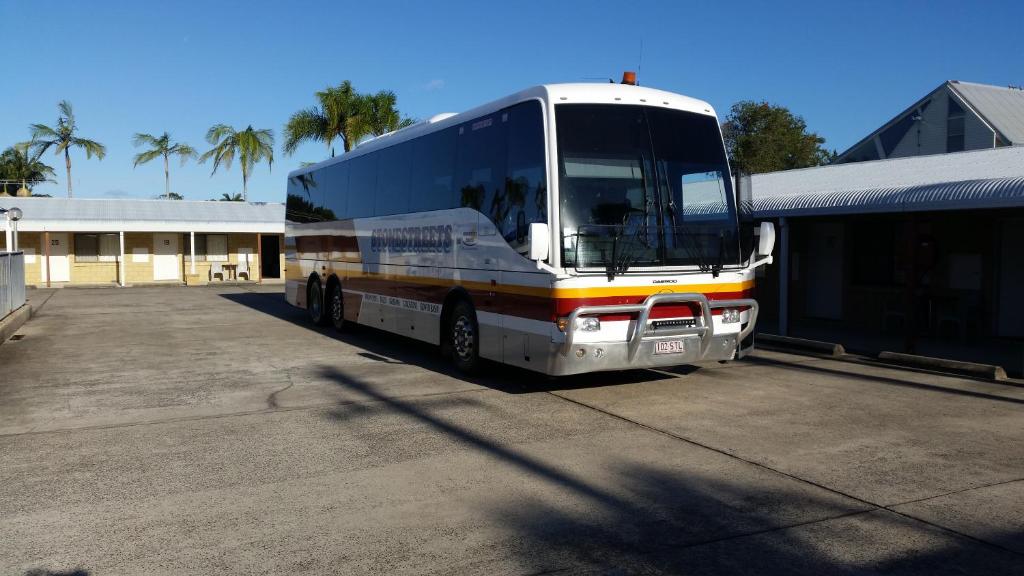 a bus parked in a parking lot next to a building at Sandcastle Motel Tin Can Bay in Tin Can Bay