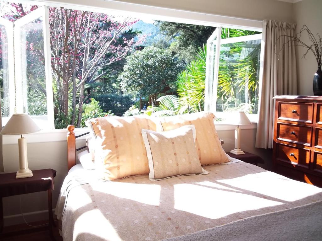 een slaapkamer met een bed voor een raam bij Coromandel Eco Sanctuary in Coromandel Town