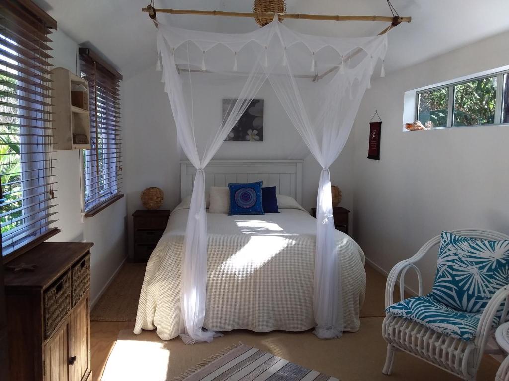 a bedroom with a white bed with a canopy at Bali Haven in Coromandel Town