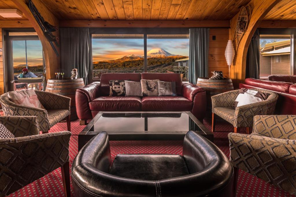 ein Wohnzimmer mit einem Ledersofa und Stühlen in der Unterkunft Skotel Alpine Resort in Whakapapa Village