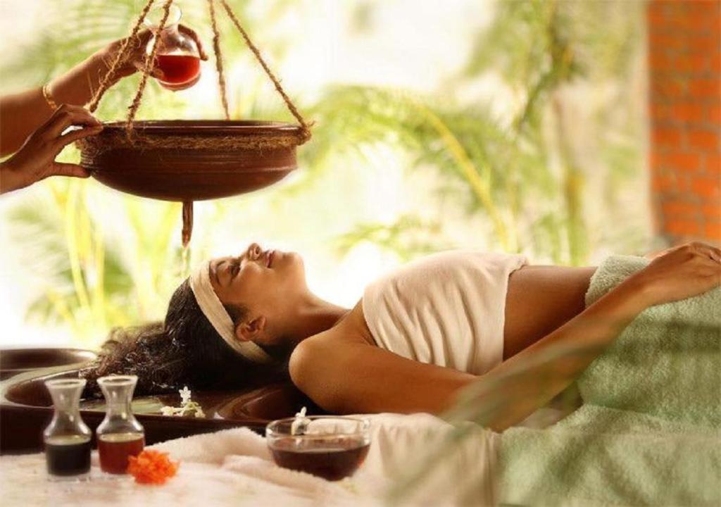 a woman laying on a bed with a bird feeder at Nilaveli Ayurveda Center in Nilaveli