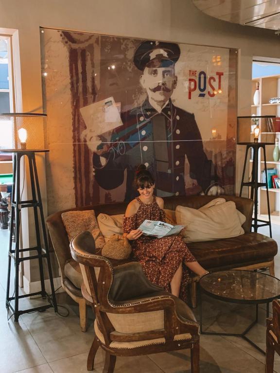 a young girl sitting in a chair in front of a painting at The Post Hostel Jerusalem in Jerusalem