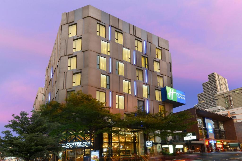 Holiday Inn Express Bangkok Sukhumvit 11, an IHG Hotel في بانكوك: مبنى طويل على شارع المدينة في الليل