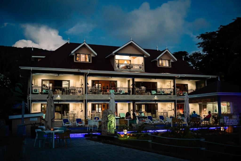 a hotel at night with people sitting on the patio at CocoLux Luxury Apartments in La Digue