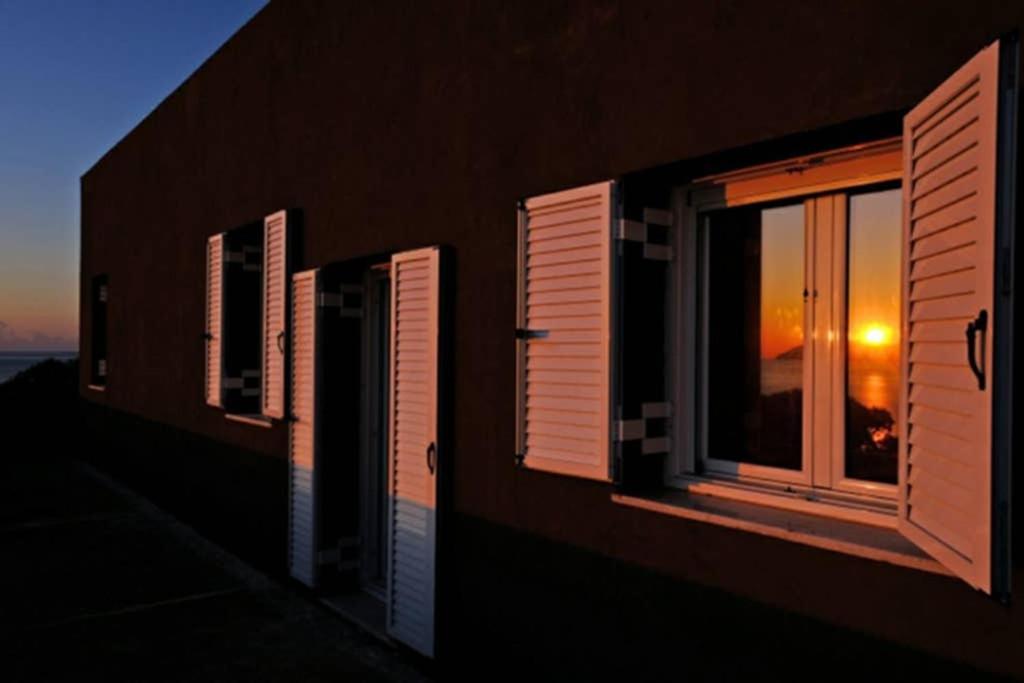 Platia Ammos的住宿－Athena s House，两扇窗户,建筑背景是日落
