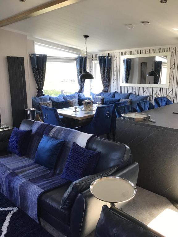 スケッグネスにあるSouthview VIP Lodge Skegness Stunning setting and location Outdoor decking area fitted to a 5 star standardのリビングルーム(青いソファ、椅子付)