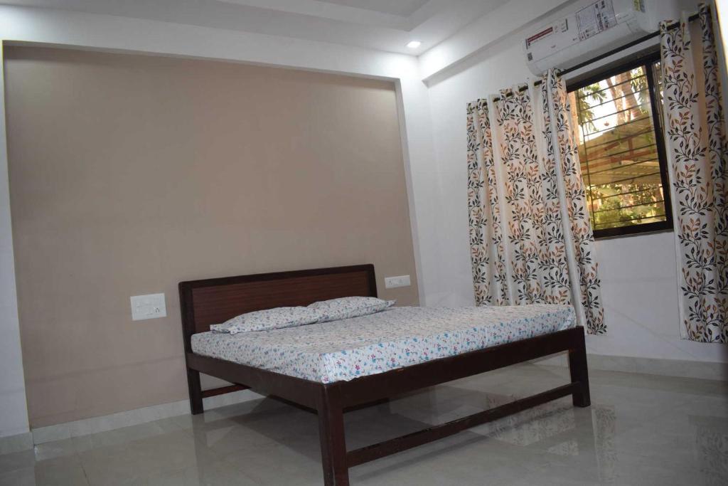 ein kleines Bett in einem Zimmer mit Fenster in der Unterkunft Smita Villa in Alibag