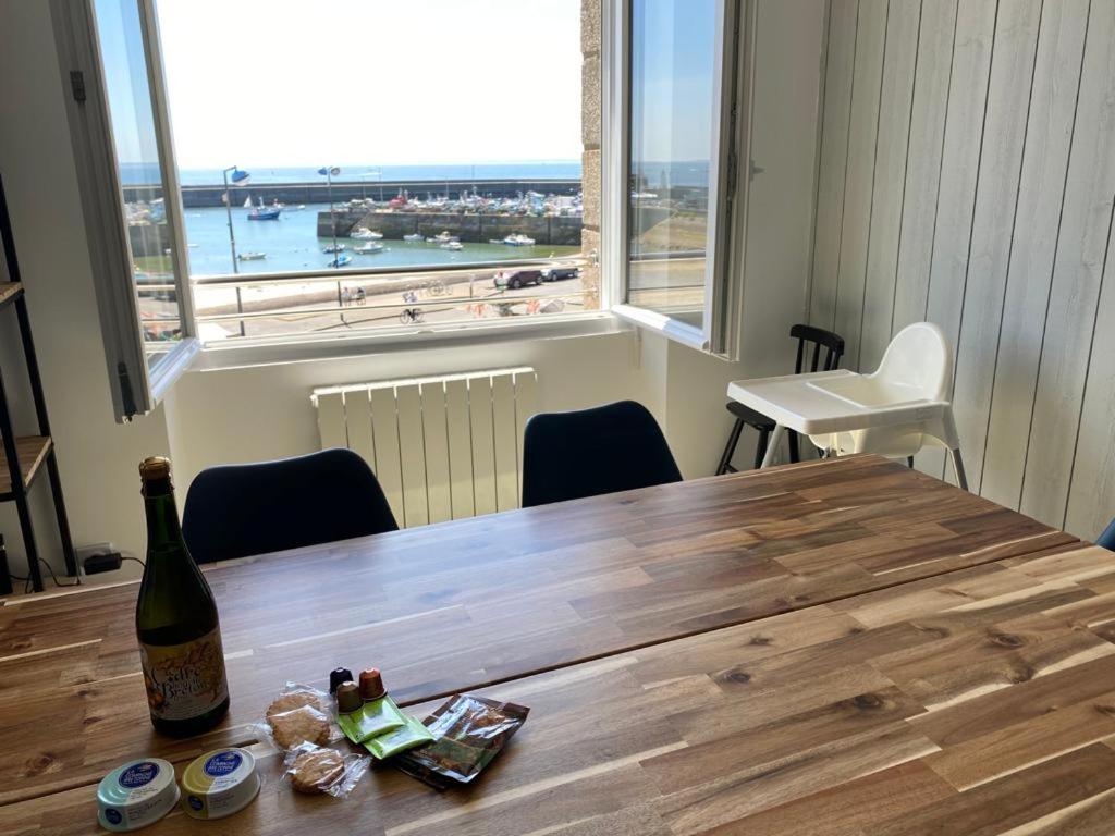 uma garrafa de vinho sentada numa mesa de madeira com uma janela em Appartement Quiberon em Quiberon