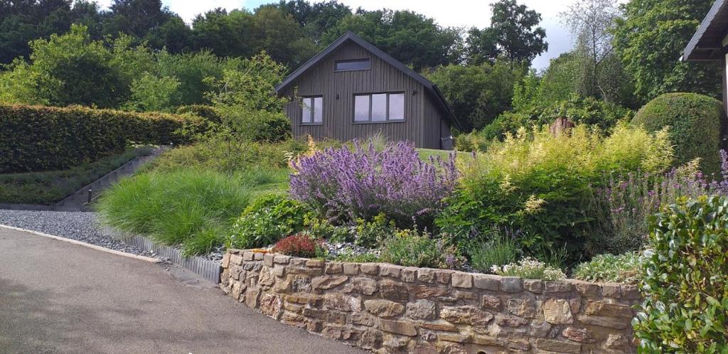 un jardin avec un mur en pierre et une petite maison dans l'établissement Le Petit Moussis, à Stavelot