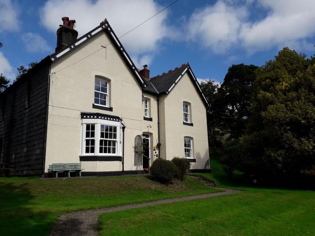 una casa blanca con un banco delante en The Old Vicarage en Llanidloes